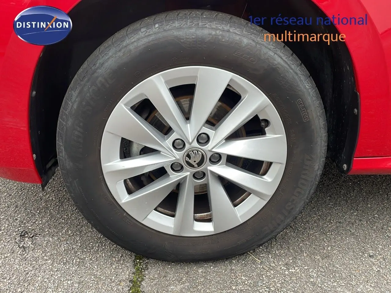 Gros plan sur la roue avant gauche d'un Skoda Kamiq rouge Velvet Metal avec jante argentée à dix branches.