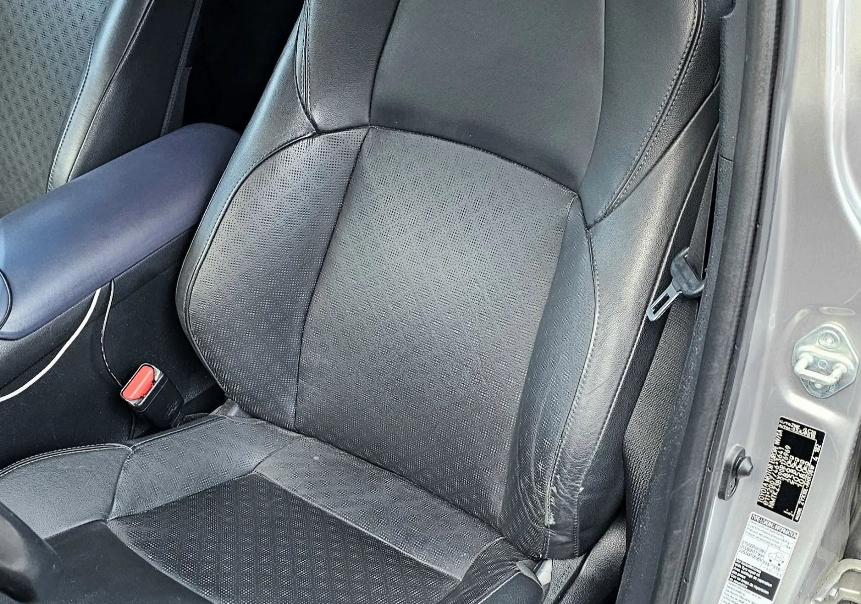 Vue intérieure côté conducteur du siège en cuir noir du Toyota C-HR hybride gris 2018, avec portière ouverte.