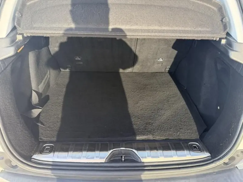Vue plongeante sur le coffre ouvert du Peugeot 2008 blanc, montrant un espace de rangement propre et spacieux.