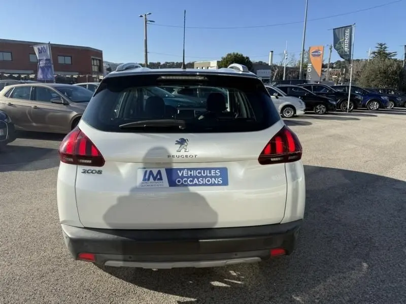 Vue arrière d’un Peugeot 2008 blanc de 2018, version 1.2 PureTech 110 Allure, sur un parking extérieur ensoleillé.