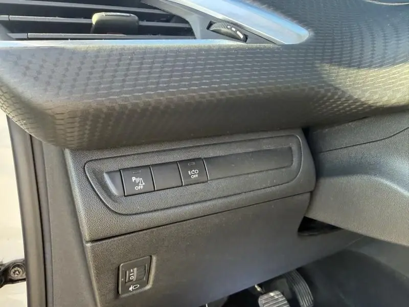 Détail intérieur côté gauche du tableau de bord du Peugeot 2008 blanc 2018, boutons de contrôle ECO et assistance stationnement.