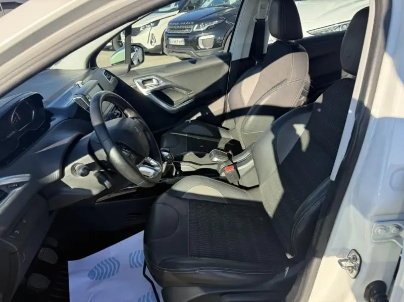 Vue intérieure côté conducteur de la Peugeot 2008 blanche 2018, montrant les sièges et le volant avec boîte manuelle.