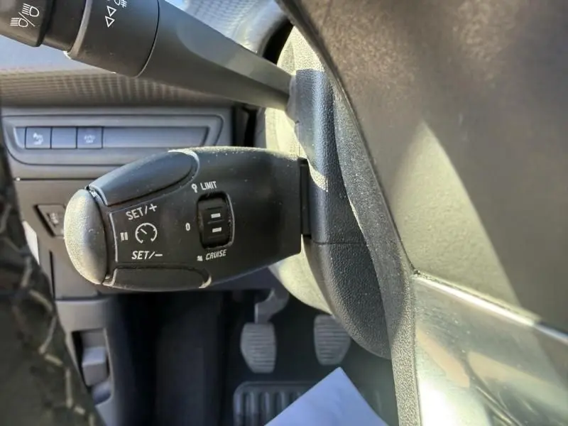 Gros plan sur le commodo de régulateur de vitesse dans l’habitacle d’un Peugeot 2008 blanc, côté conducteur.