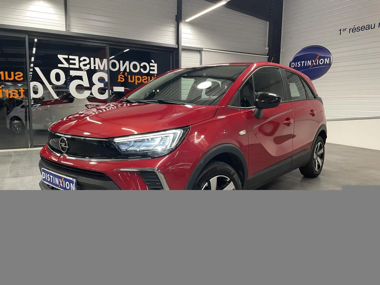 Opel Crossland rouge clair vue 3/4 avant droit, avec calandre noire et jantes bicolores 16 pouces.