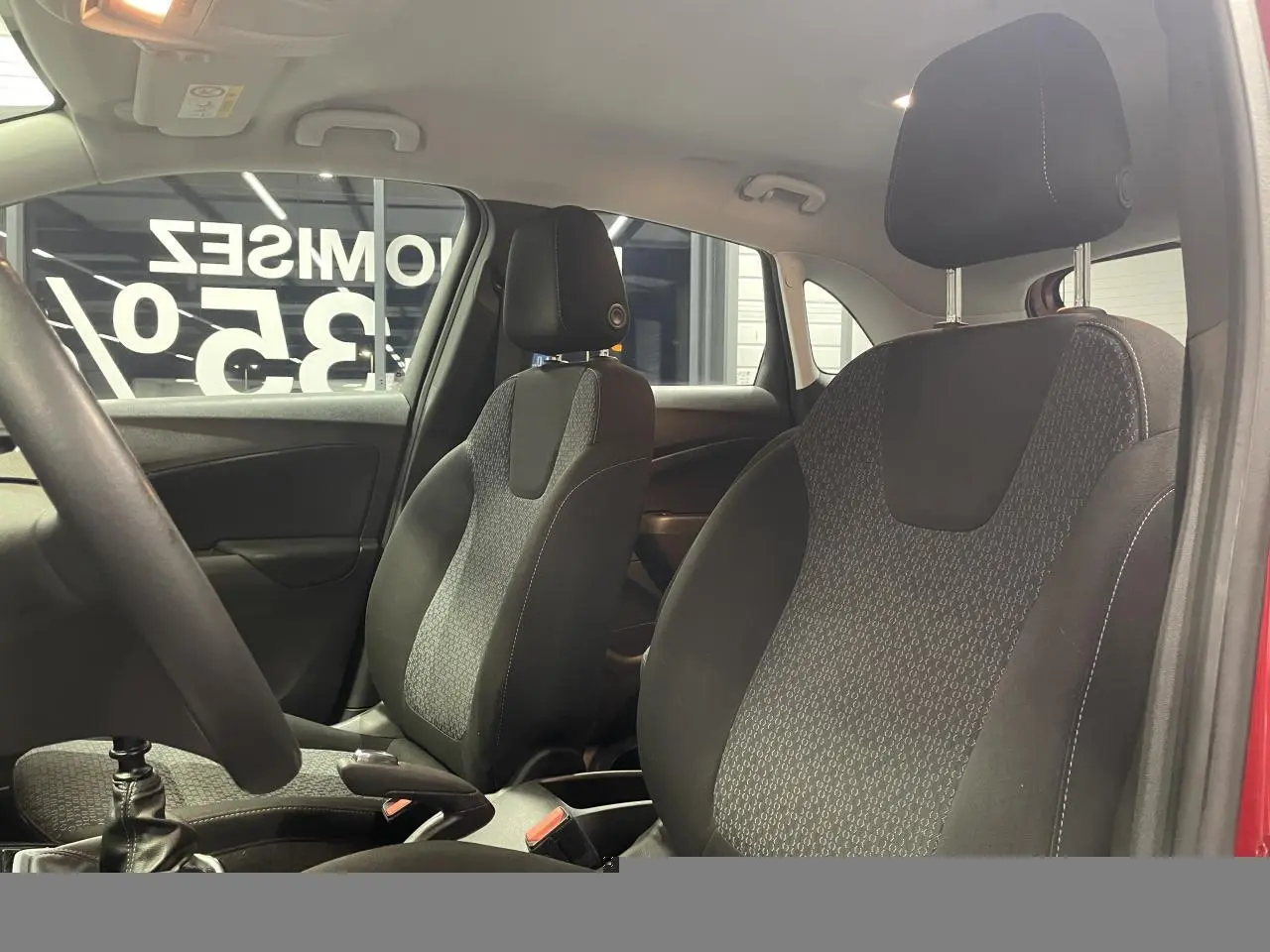Vue intérieure des sièges avant en tissu noir et gris de l’Opel Crossland rouge clair, avec volant partiellement visible.