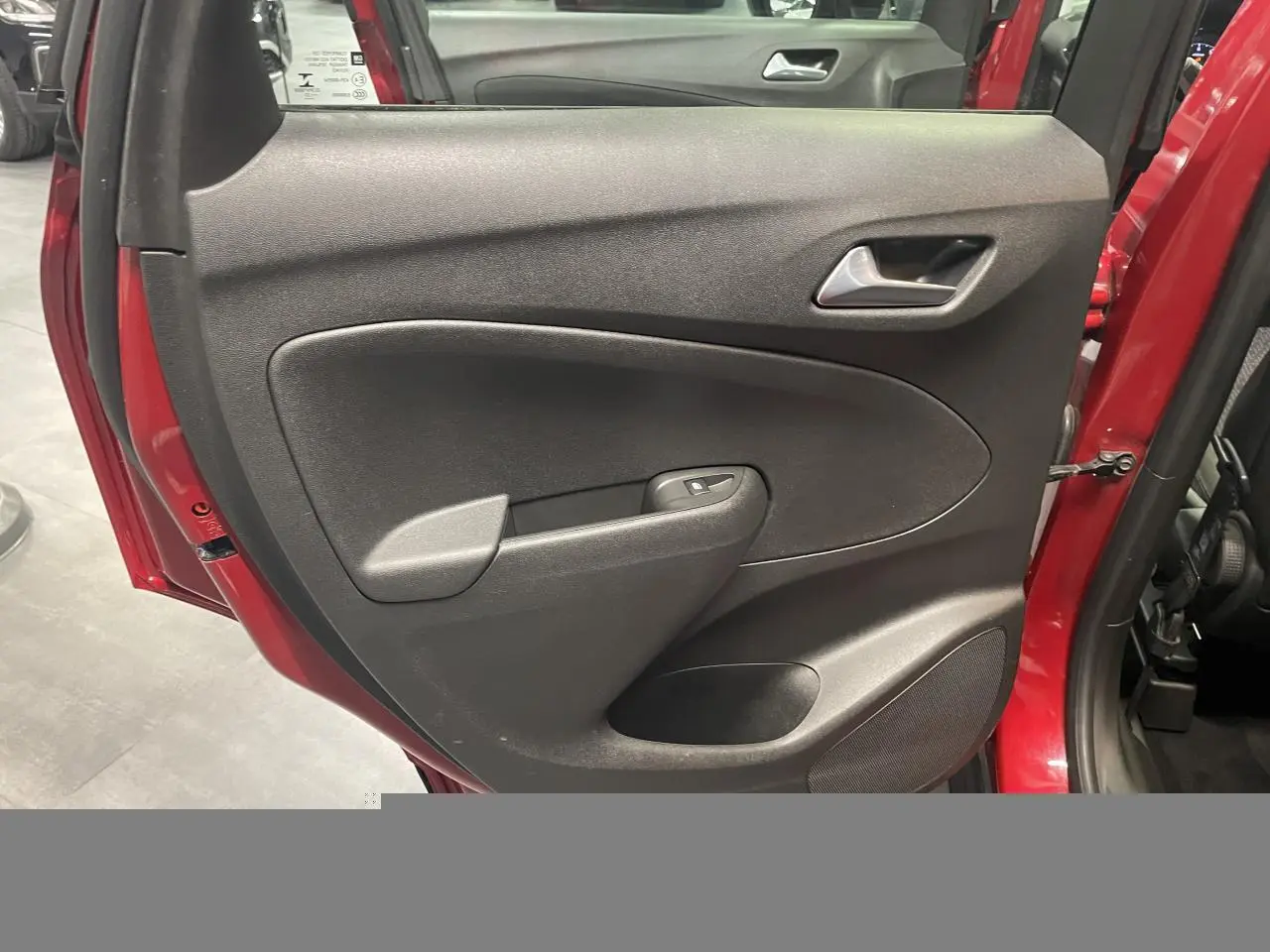 Vue rapprochée de la porte arrière droite rouge clair de l'Opel Crossland avec panneau intérieur noir et commande de vitre.