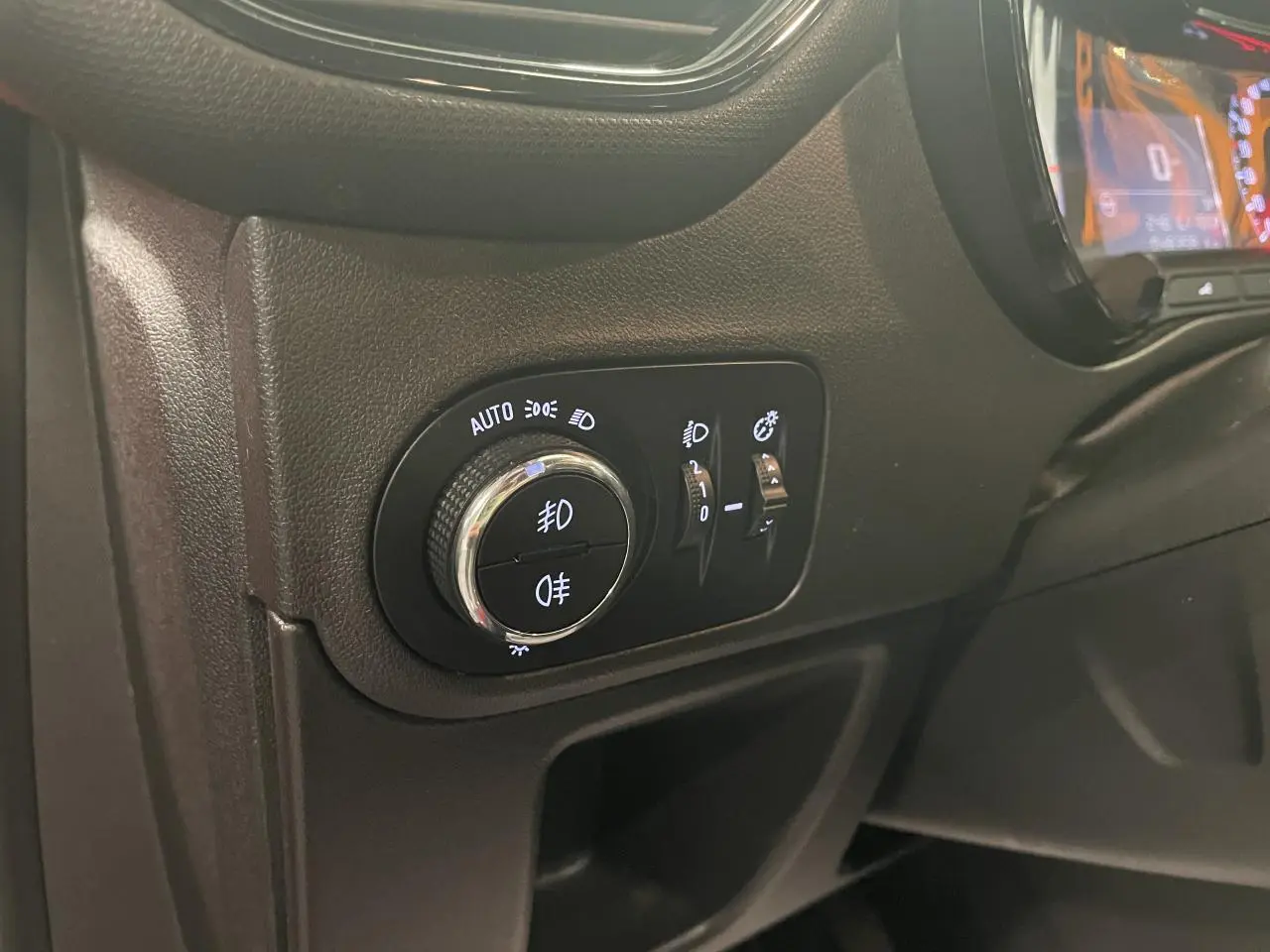 Gros plan sur le tableau de bord côté gauche de l’Opel Crossland rouge clair, montrant les commandes d’éclairage et le compteur digital.