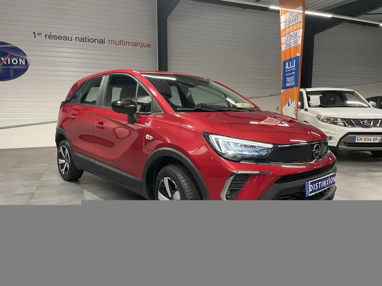 Opel Crossland rouge clair en 3/4 avant droit, avec coques de rétroviseurs noires et jantes bicolores 16 pouces.