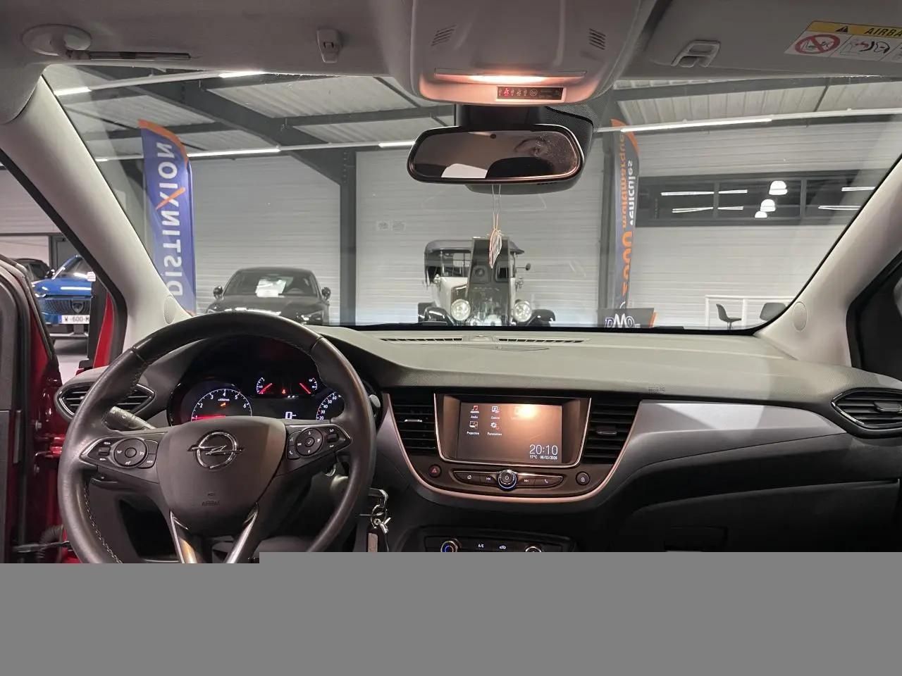 Vue intérieure avant de l'Opel Crossland rouge clair 2022, avec tableau de bord et écran tactile central allumé.