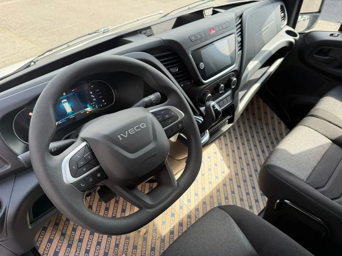 Vue intérieure du poste de conduite de l’Iveco Daily 2026, volant multifonction et tableau de bord moderne en gris foncé.