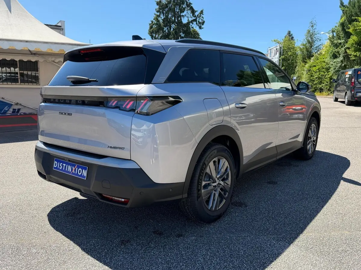 Vue 3/4 arrière droite d’un Peugeot 5008 gris clair hybride, avec feux LED et vitres teintées.