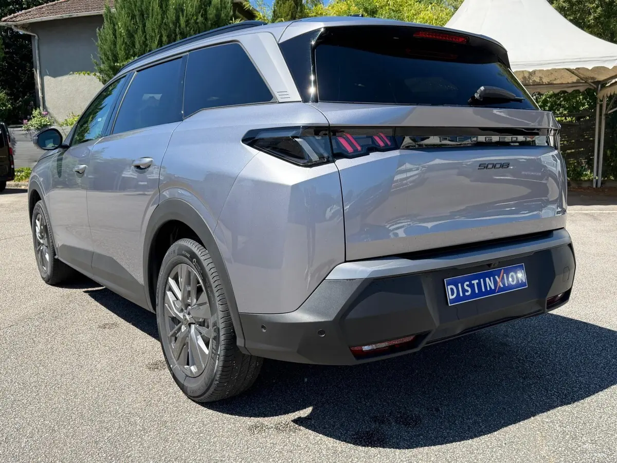 Vue 3/4 arrière droite du Peugeot 5008 gris clair 2025 avec feux arrière LED et vitres teintées.