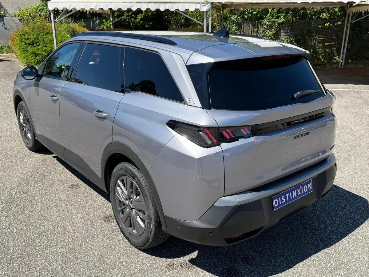 Vue 3/4 arrière droite du Peugeot 5008 gris clair, avec feux arrière LED et vitres teintées.