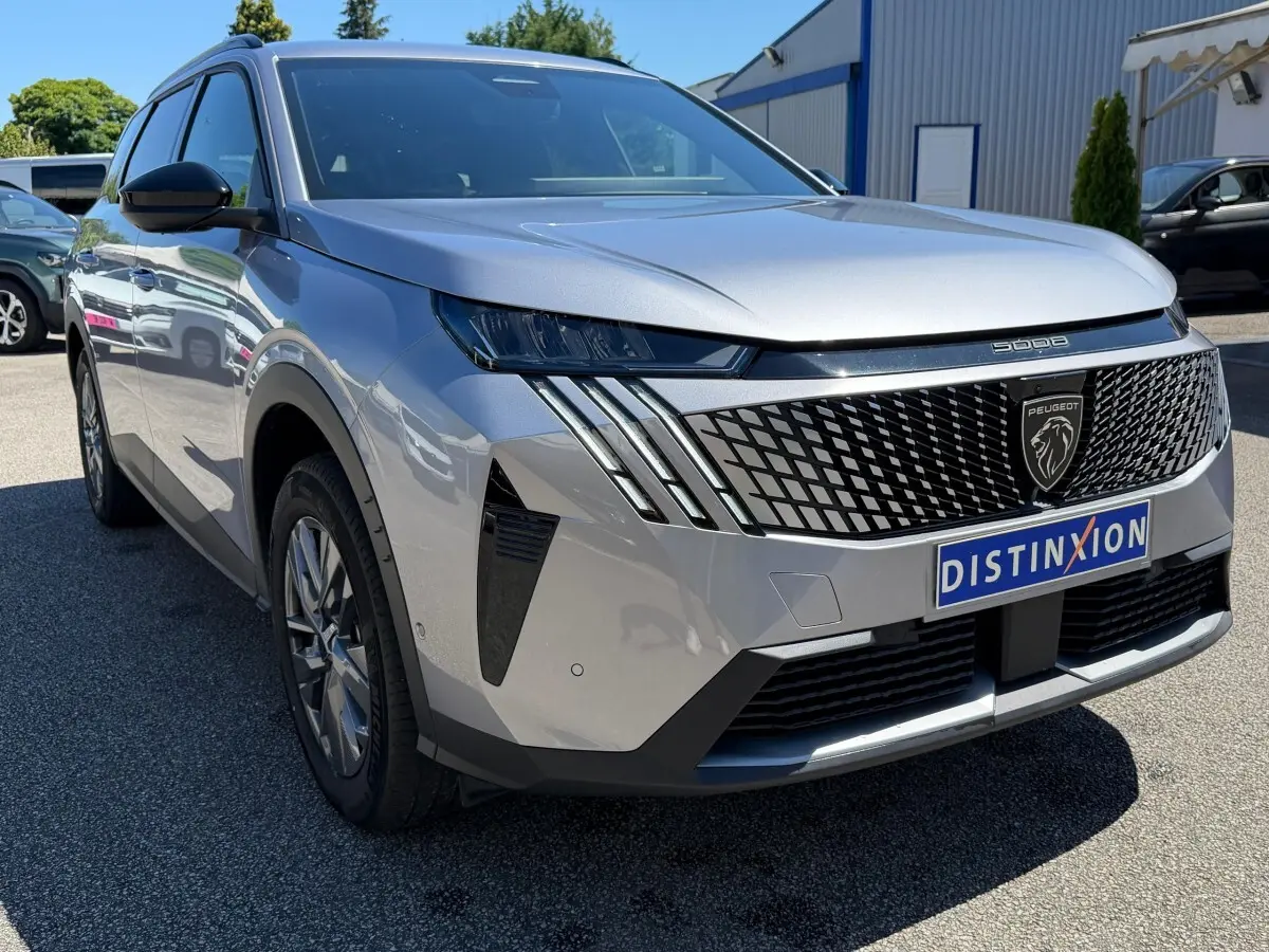 Peugeot 5008 gris clair vue 3/4 avant avec calandre noire à motif géométrique et feux LED distinctifs.