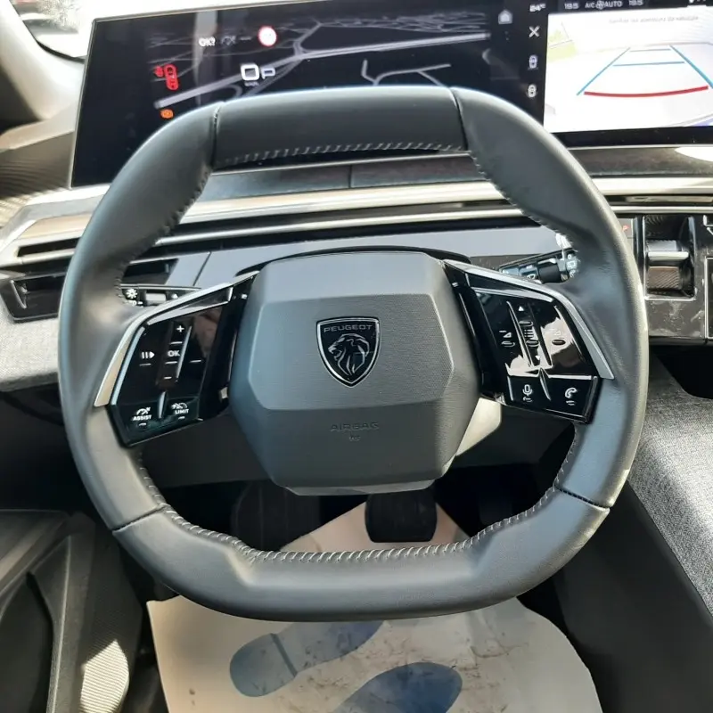 Vue rapprochée du volant cuir noir du Peugeot 5008 2025 avec commandes multifonctions et tableau de bord numérique.