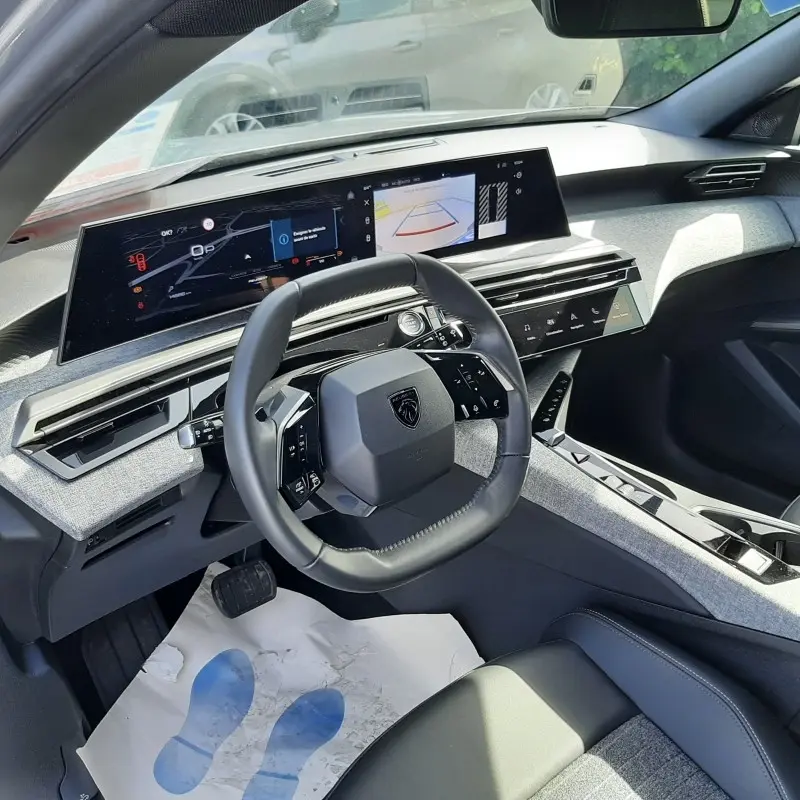 Vue intérieure avant droite du Peugeot 5008 gris clair, volant compact et double écran tactile large au tableau de bord.