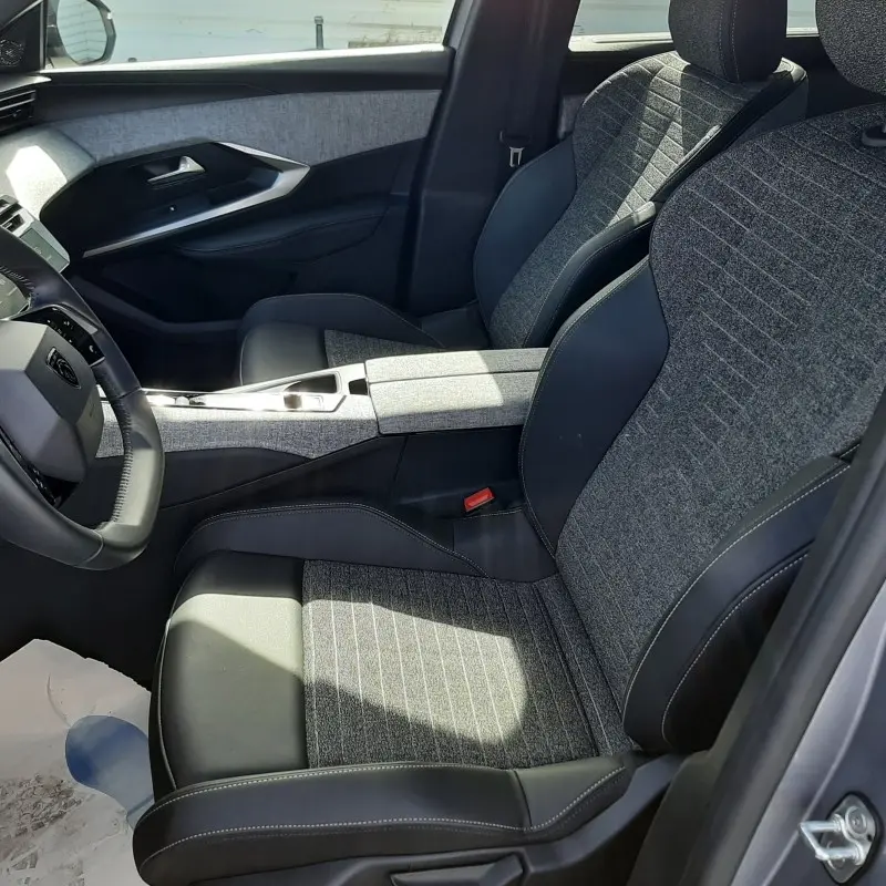 Vue intérieure côté conducteur du Peugeot 5008 2025, sièges tissu gris et cuir noir avec console centrale assortie.