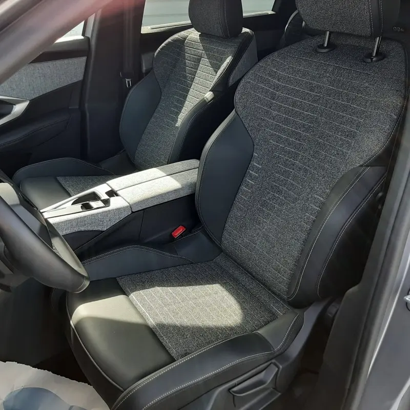 Vue intérieure côté conducteur du Peugeot 5008 gris clair 2025, sièges tissu et cuir avec console centrale assortie.