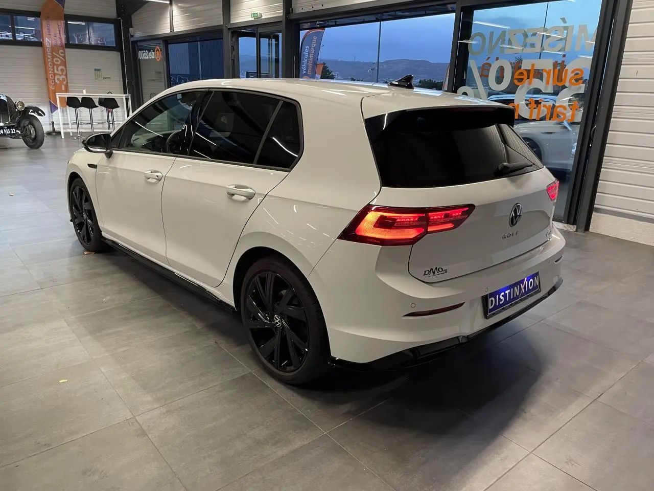 Volkswagen Golf 1.5 eTSI 2024 blanc vue 3/4 arrière droit avec jantes noires et vitres teintées.