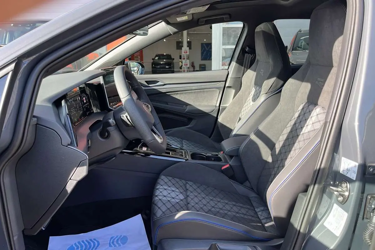 Vue intérieure côté conducteur de la Volkswagen Golf gris dauphin, sièges sport R-Line en tissu et alcantara avec surpiqûres bleues.