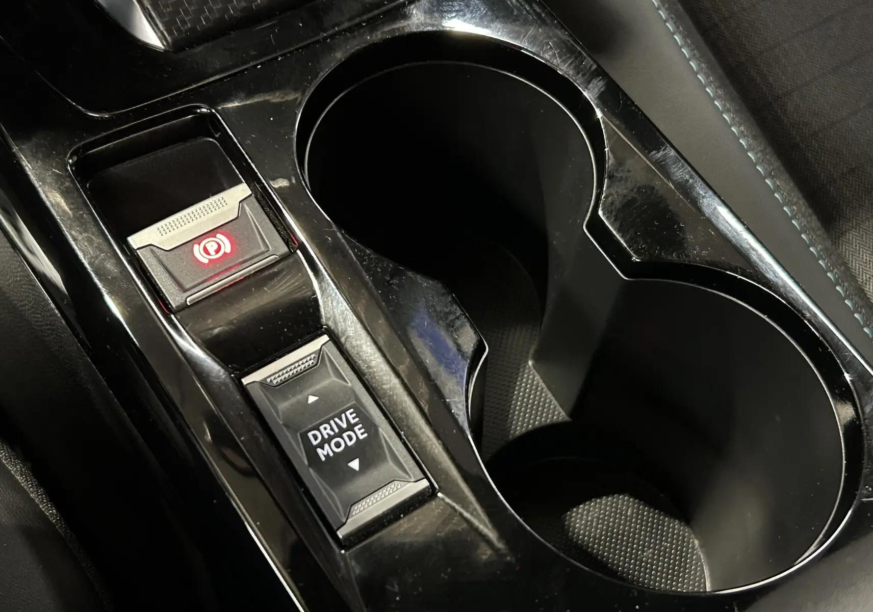 Gros plan sur la console centrale noire du Peugeot 2008 gris Artense, avec bouton frein à main électronique et mode de conduite.