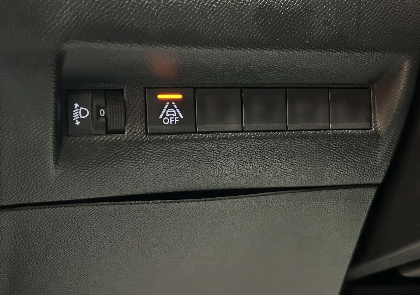 Gros plan sur les commandes intérieures noires avec bouton d'alerte de maintien de voie activé dans une Peugeot 2008 gris Artense.
