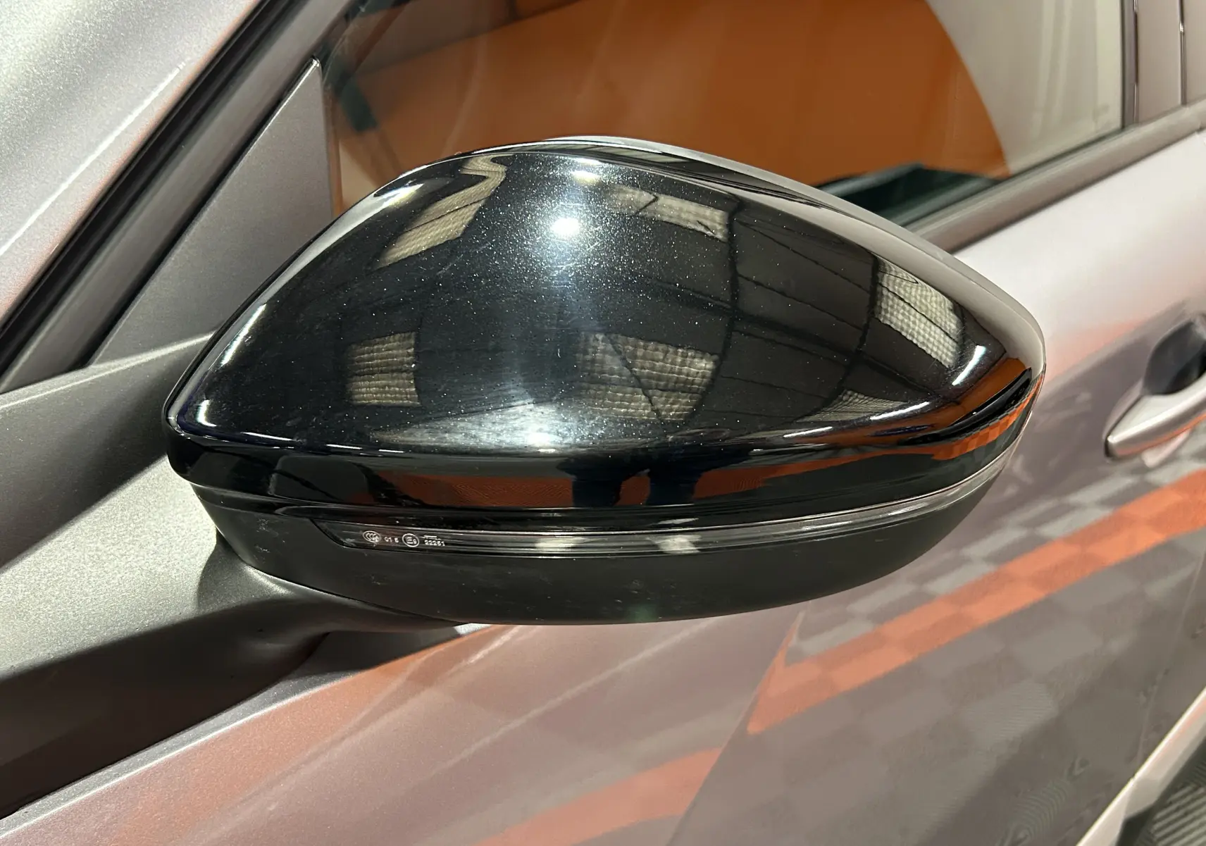 Rétroviseur noir brillant côté gauche d’un Peugeot 2008 gris Artense, vue rapprochée sur la portière avant.