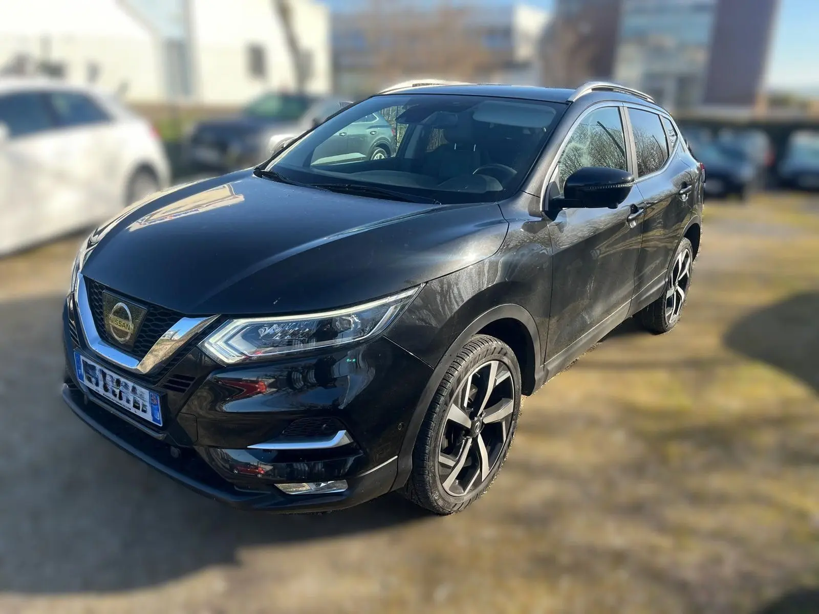 Vue 3/4 avant droit d'un Nissan Qashqai noir avec jantes alliage et calandre chromée dans un garage en bois.