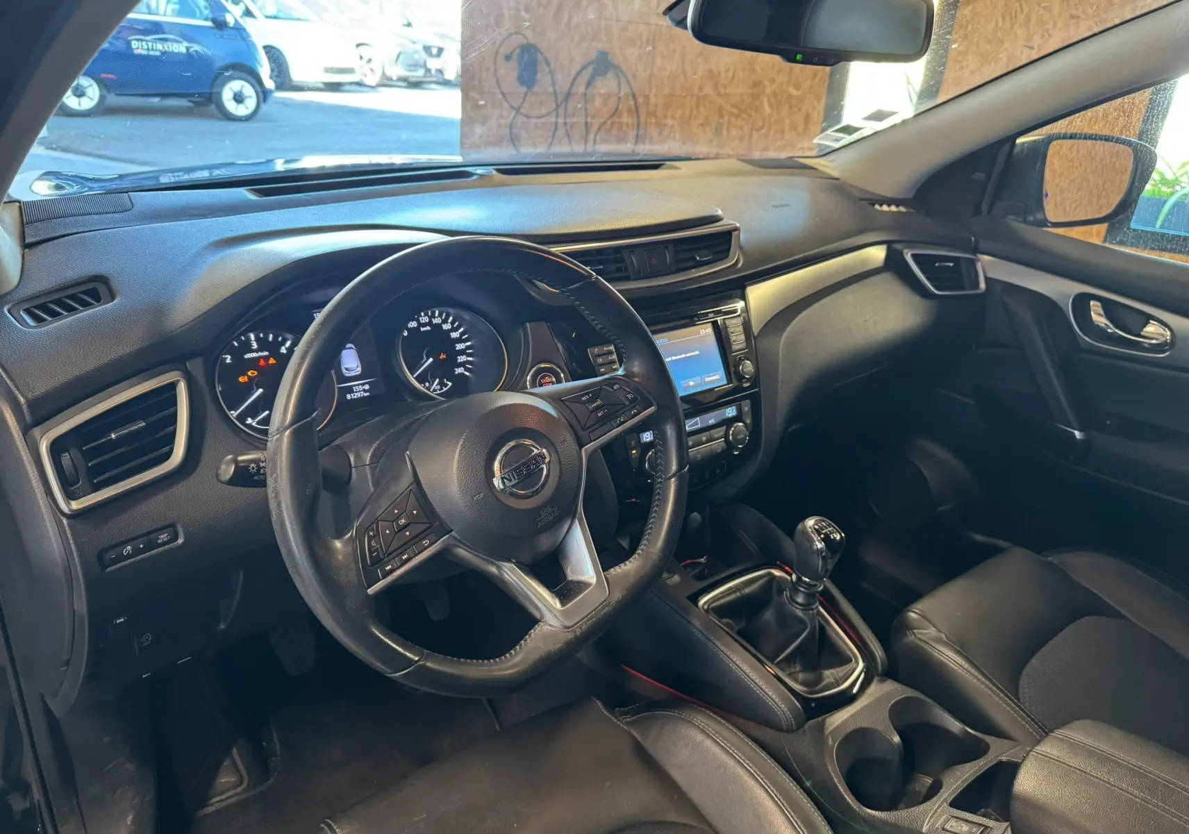 Intérieur noir du Nissan Qashqai II PH2 2017 vu côté conducteur, volant cuir multifonctions et levier de vitesse manuel visibles.