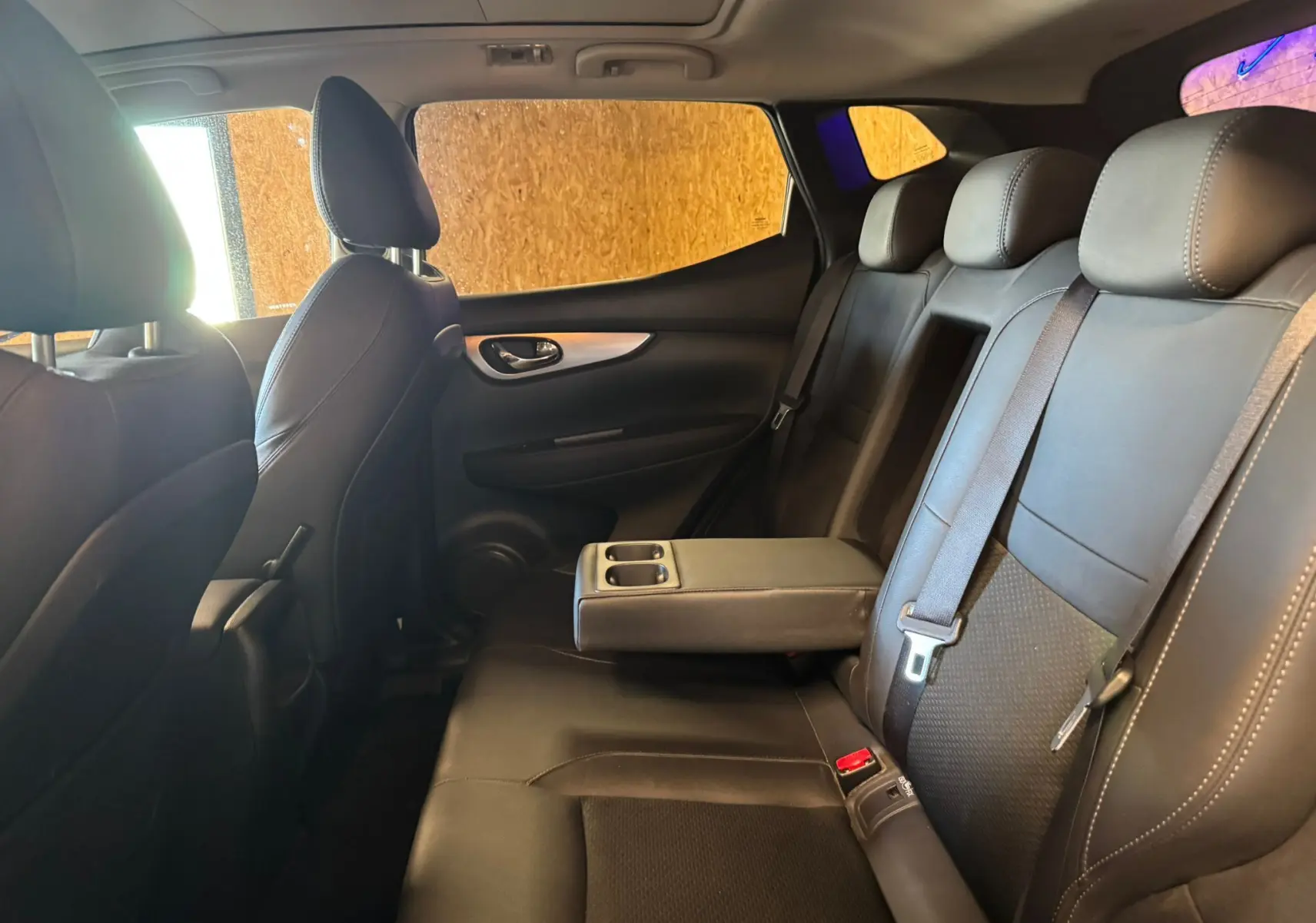 Vue intérieure côté droit des sièges arrière en cuir noir avec accoudoir central abaissé du Nissan Qashqai II PH2 2017.