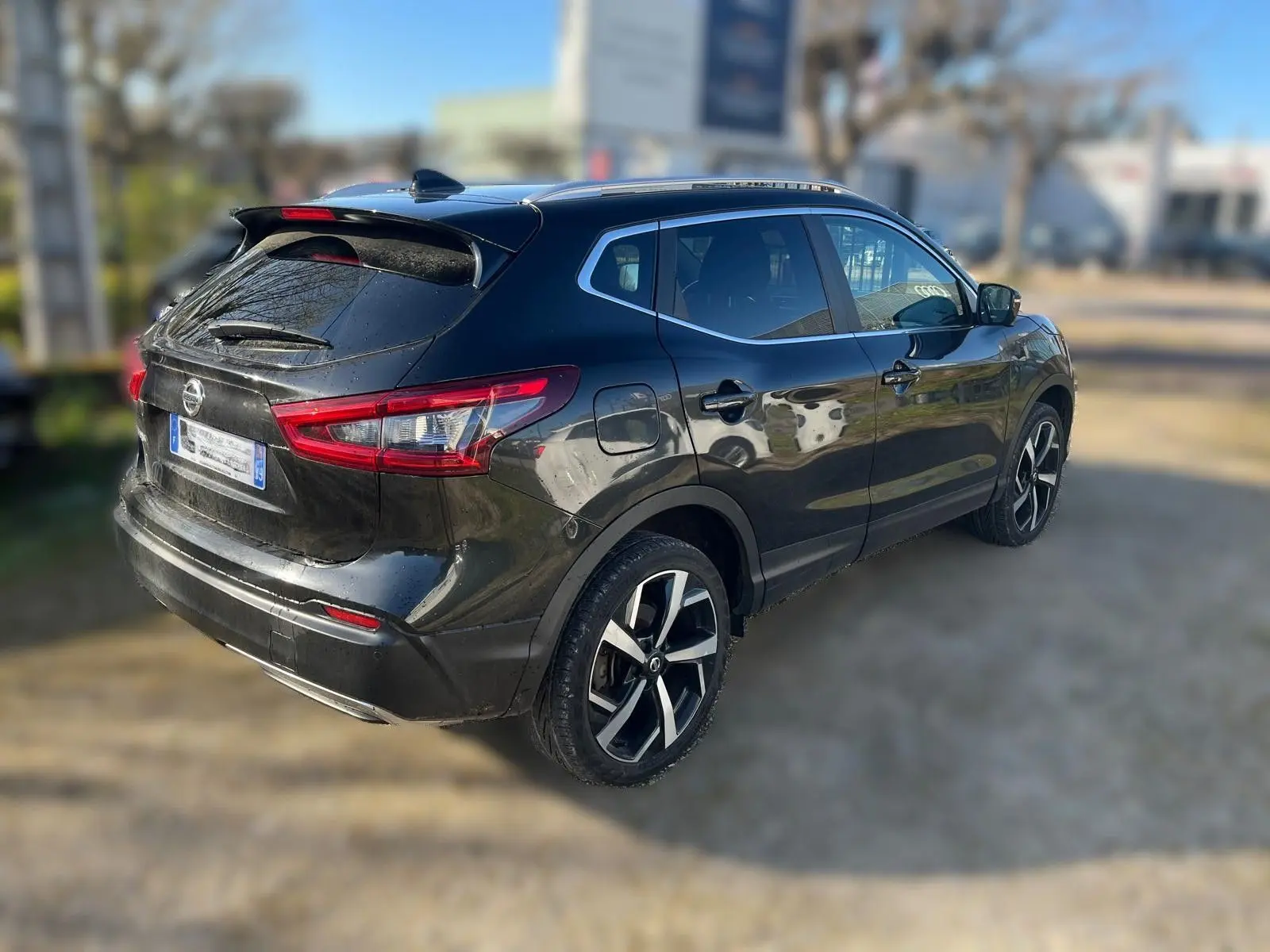 Vue avant d'un Nissan Qashqai II PH2 noir avec calandre chromée et plaque Distinxion en intérieur d'atelier.