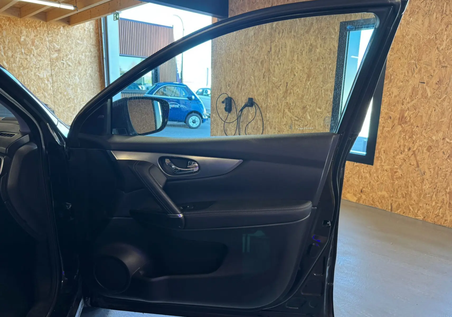 Vue intérieure de la porte avant gauche noire du Nissan Qashqai II PH2 2017, avec poignée chrome et garniture cuir.