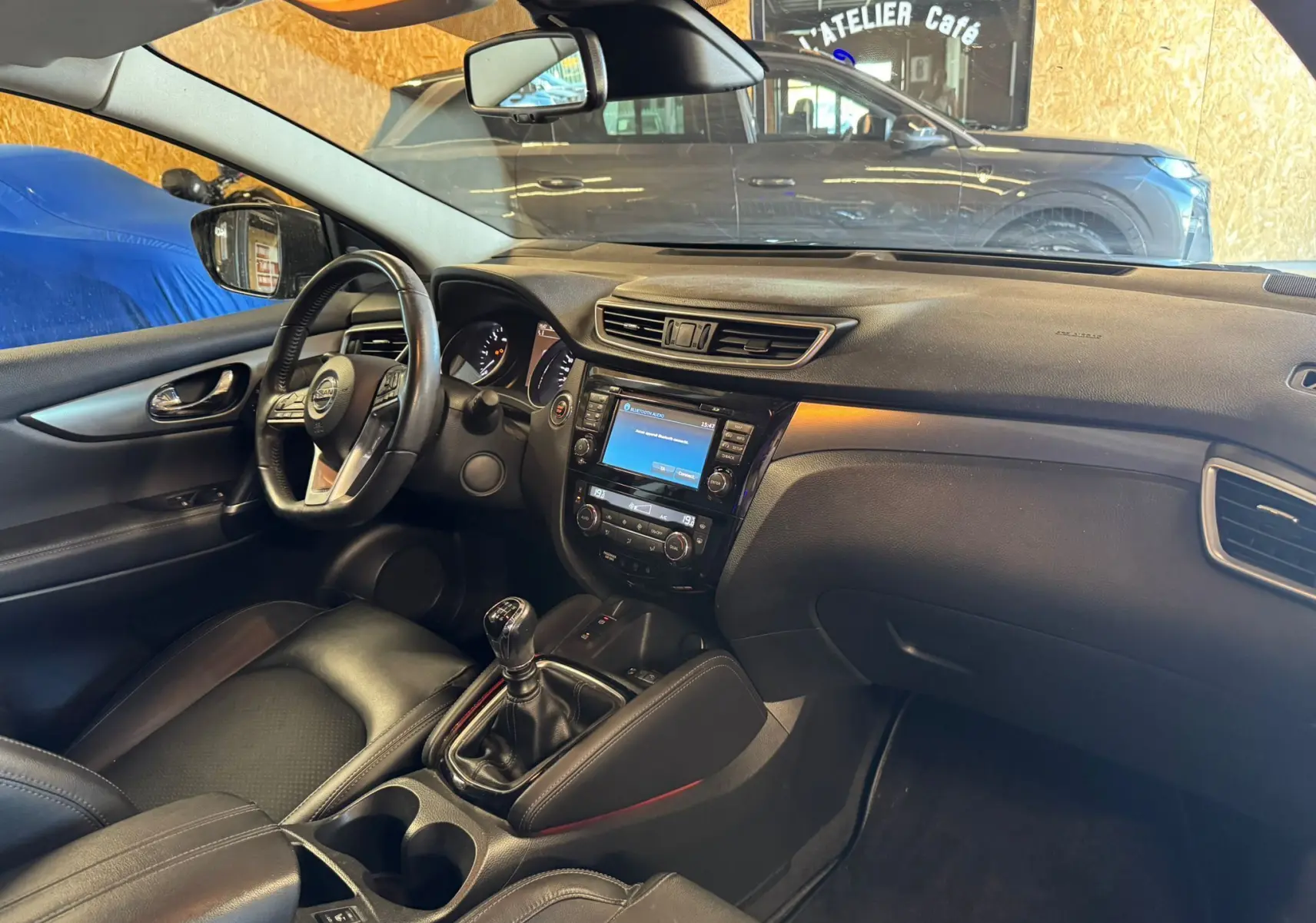 Intérieur noir du Nissan Qashqai II PH2 2017, vue côté conducteur avec volant cuir et console centrale manuelle.