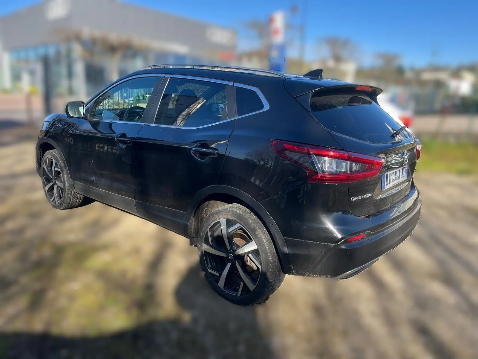 Nissan Qashqai noir vu de face en léger 3/4 avant droit, avec calandre chromée et jantes alu visibles.