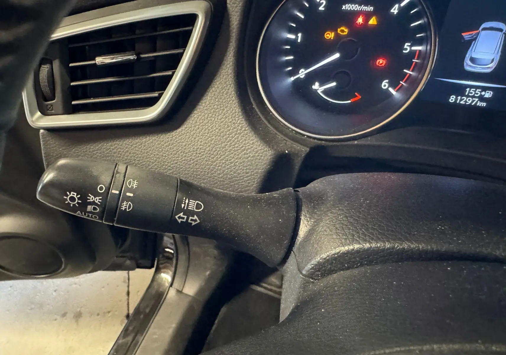 Gros plan sur la commande des phares et clignotants côté gauche du tableau de bord noir du Nissan Qashqai 2017.