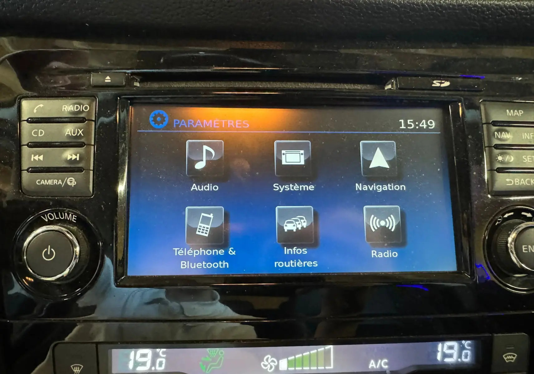 Écran tactile central du Nissan Qashqai noir, affichant le menu paramètres avec options audio et navigation.