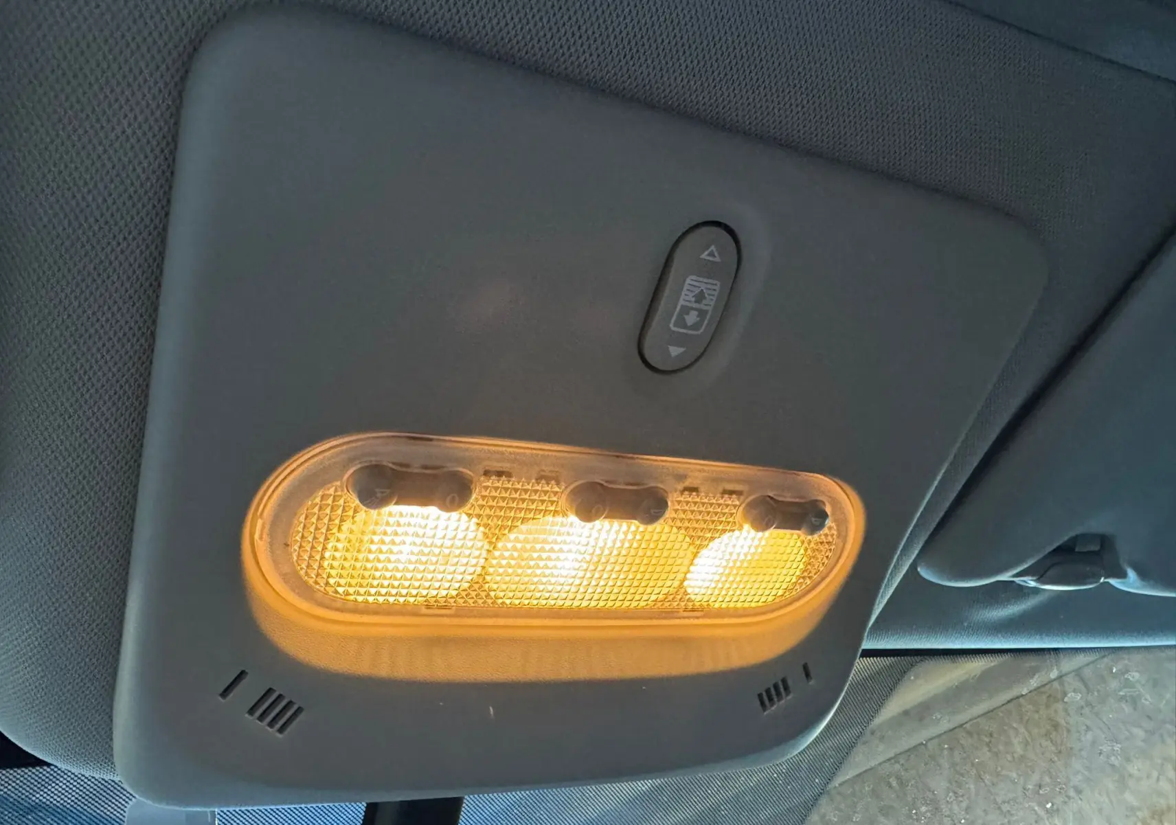 Plafonnier intérieur allumé avec commandes d'ouverture du toit panoramique du Nissan Qashqai noir, vue de dessous.