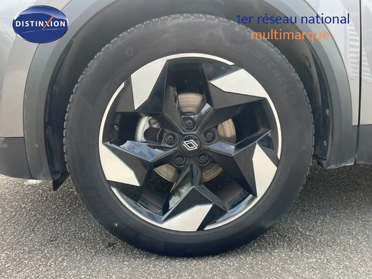 Gros plan sur la roue avant droite du Renault Captur gris Cassiopée métal avec jante alliage noire et argentée au design étoilé.