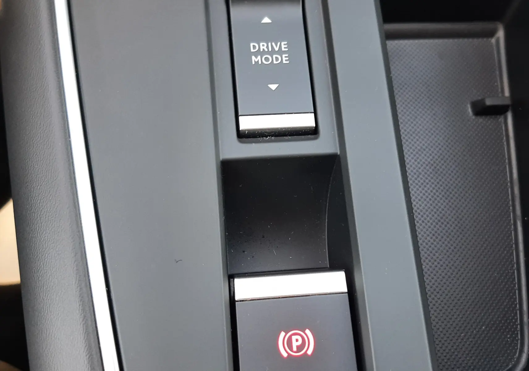 Gros plan sur la console centrale noire du Citroën C5 Aircross Ph.2 Hybrid avec bouton Drive Mode et frein à main électrique.