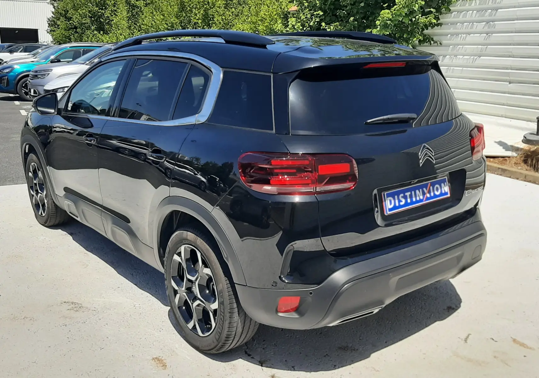 Vue 3/4 arrière droite d'un Citroën C5 Aircross noir Perla Nera avec jantes bi-ton et feux arrière LED distinctifs.