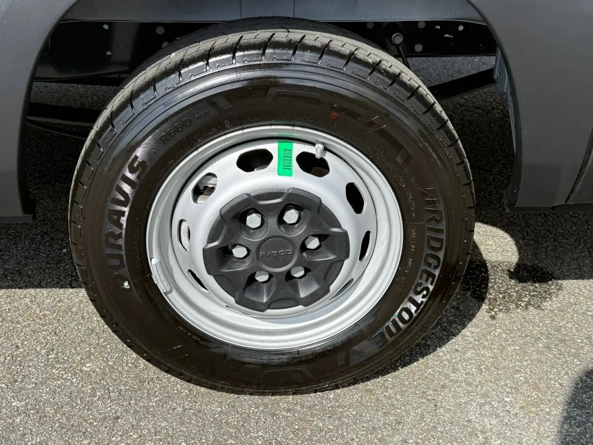 Gros plan sur la roue avant droite du fourgon Iveco Daily blanc, jante acier grise avec pneu Bridgestone.