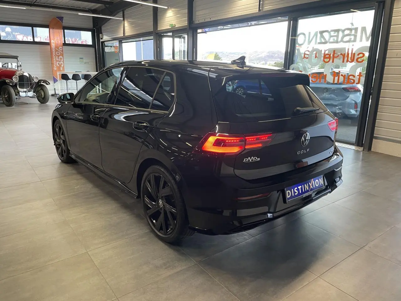 Volkswagen Golf VIII R-Line Black noir métal vue 3/4 arrière droit avec jantes noires 18 pouces en intérieur showroom.