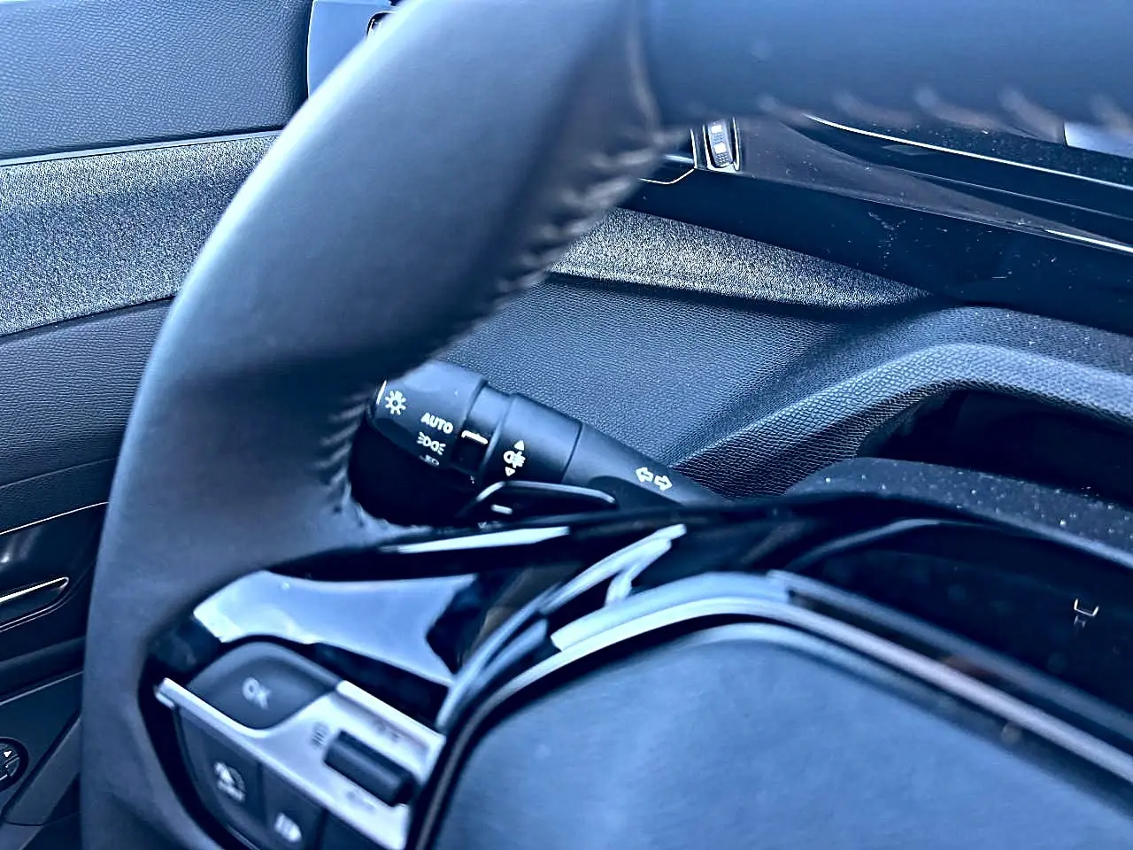 Gros plan sur le volant noir et la commande des phares du Peugeot 308 1.5 BlueHDi 130 Allure 2025.