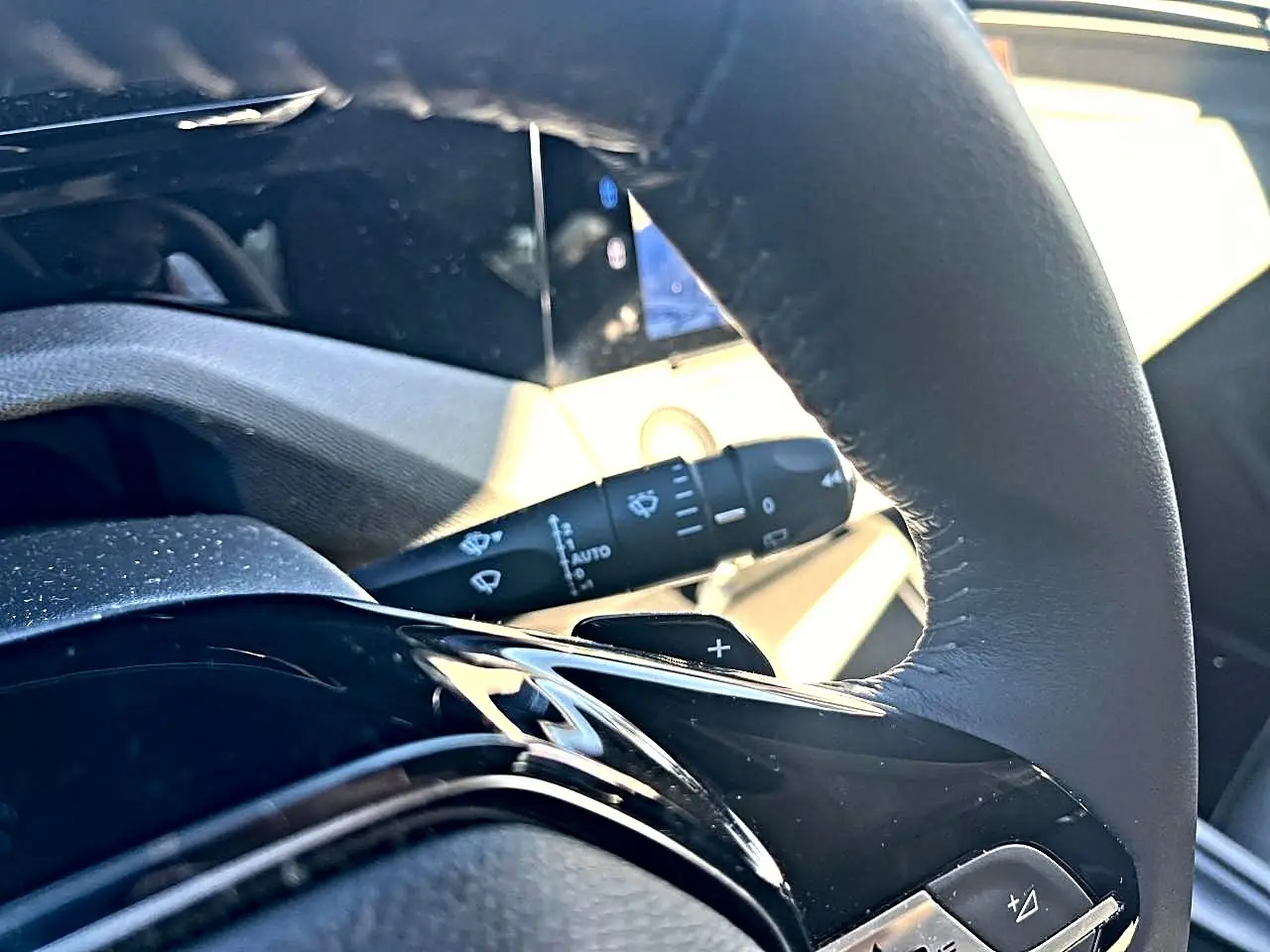 Gros plan sur le volant noir de la Peugeot 308 2025 avec commandes intégrées et manette d'essuie-glace visible en arrière-plan.