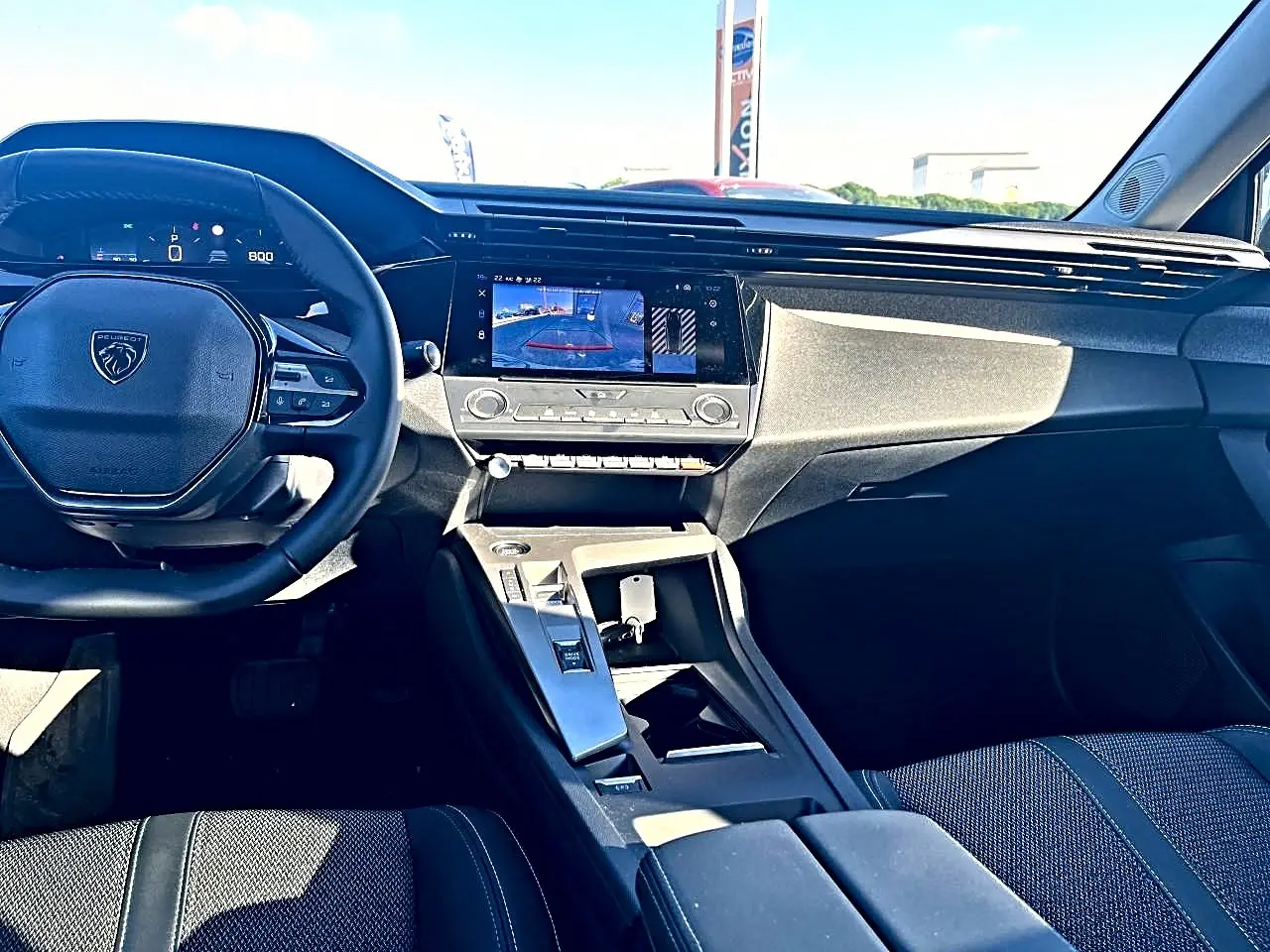 Vue intérieure avant de la Peugeot 308 2025, tableau de bord moderne avec écran tactile et volant multifonction noir.