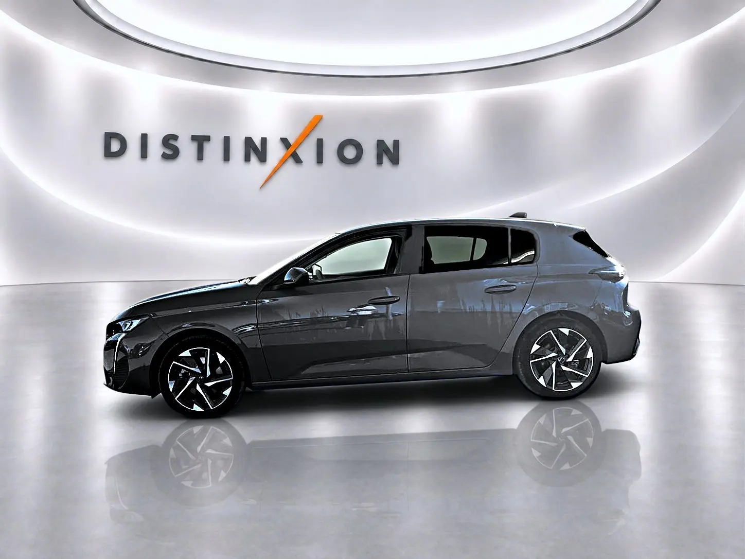 Profil gauche d'une Peugeot 308 gris selenium 2025 avec jantes alu et vitres arrière surteintées dans un showroom lumineux.