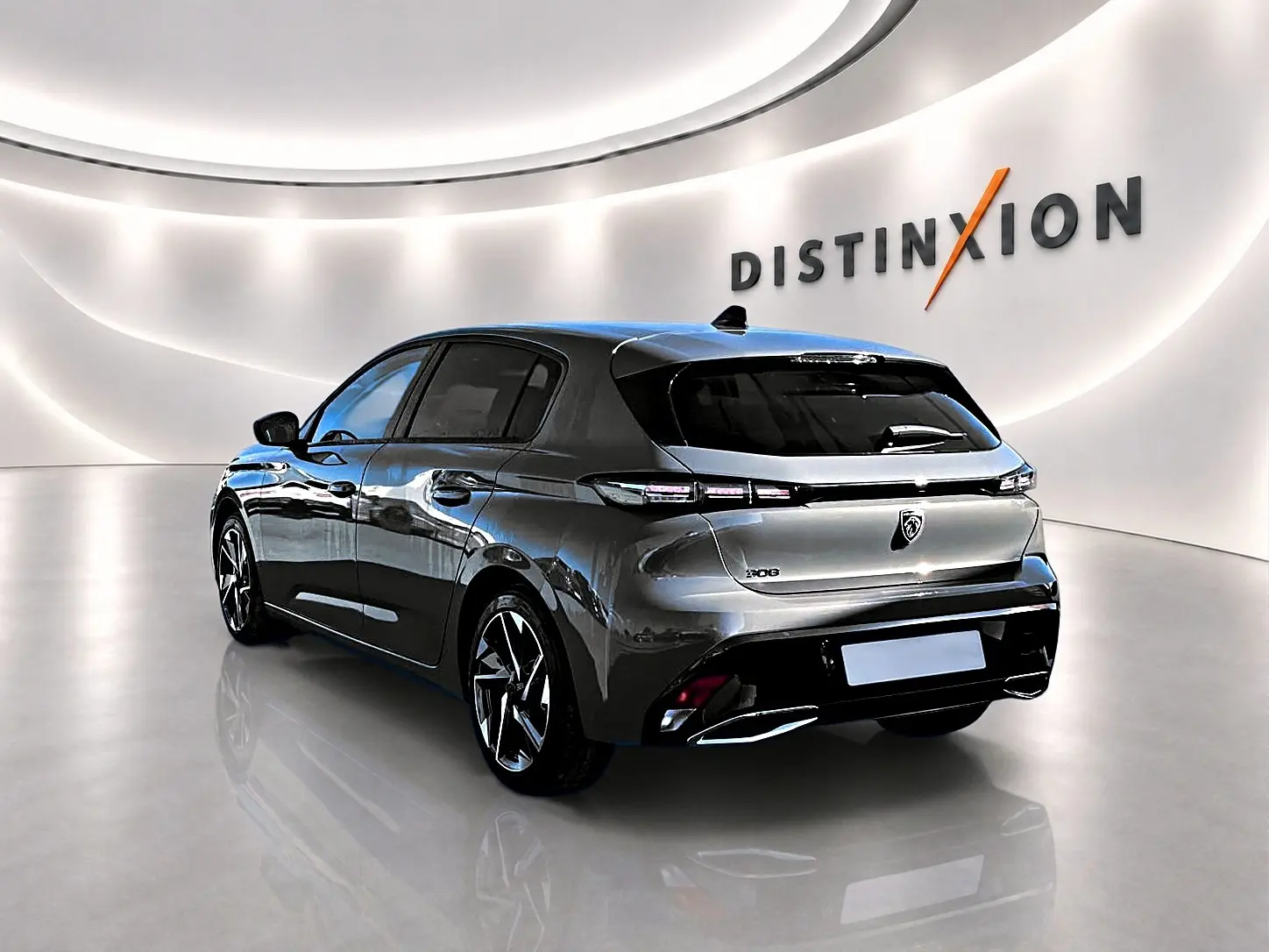 Vue 3/4 arrière droite d'une Peugeot 308 gris selenium avec jantes alu dans un showroom lumineux.