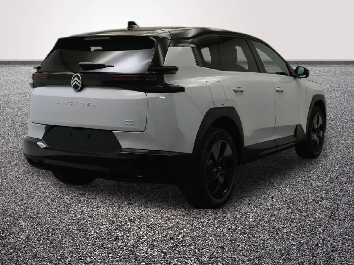 Vue 3/4 arrière droite d'une Citroën C5 Aircross blanche avec toit noir et hayon motorisé, sur sol gris.