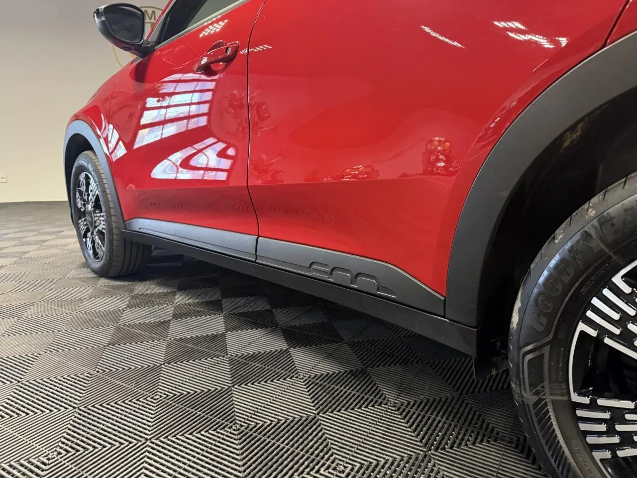 Vue latérale gauche d'une FIAT 600 rouge foncé avec jantes noires et bas de caisse noir mat distinctif.