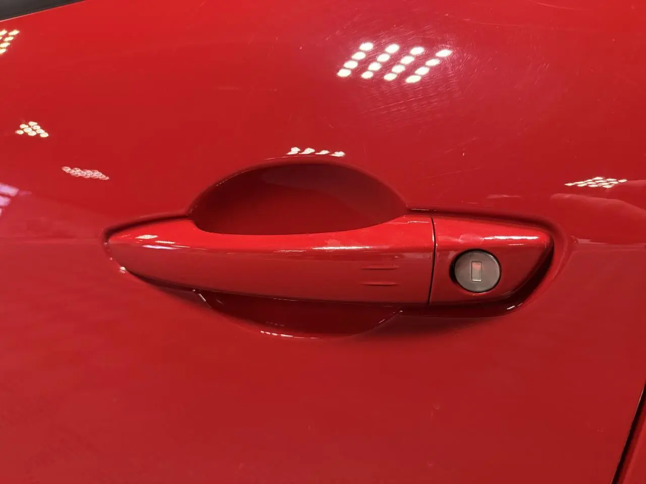 Poignée de porte rouge foncé de la FIAT 600 Hybrid 2025, avec serrure intégrée côté droit.